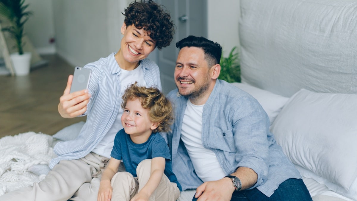 Perfect family girl guy and kid taking selfie at home in bed using smartphone